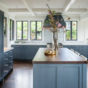 Imagen de cocina comedor en L, contemporánea, grande, con salpicadero verde, suelo de madera oscura, una isla, suelo marrón, fregadero bajoencimera, armarios con paneles empotrados, encimera de madera, electrodomésticos de acero inoxidable y puertas de armario azules