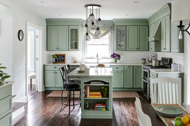 Mid-sized elegant l-shaped dark wood floor eat-in kitchen photo in San Francisco with a farmhouse sink, green cabinets, quartz countertops, white backsplash, ceramic backsplash, stainless steel appliances, an island and recessed-panel cabinets