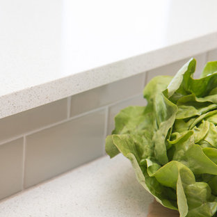 Inspiration for a large country u-shaped separate kitchen in Portland with a farmhouse sink, louvered cabinets, white cabinets, quartz benchtops, grey splashback, ceramic splashback, stainless steel appliances, vinyl floors, a peninsula and brown floor.