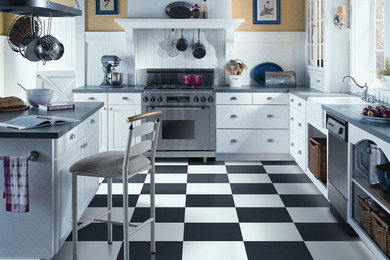 Cottage l-shaped linoleum floor and multicolored floor eat-in kitchen photo in San Francisco with a farmhouse sink, flat-panel cabinets, white cabinets, solid surface countertops, white backsplash, wood backsplash, stainless steel appliances and an island
