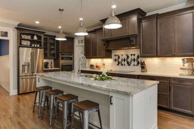 Example of a mid-sized transitional l-shaped light wood floor and beige floor kitchen design in Other with an undermount sink, recessed-panel cabinets, dark wood cabinets, marble countertops, white backsplash, subway tile backsplash, stainless steel appliances, an island and gray countertops