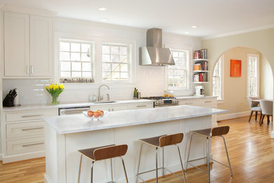 Klassisk inredning av ett mellanstort linjärt kök och matrum, med en undermonterad diskho, skåp i shakerstil, vita skåp, marmorbänkskiva, vitt stänkskydd, stänkskydd i keramik, rostfria vitvaror, ljust trägolv och en köksö