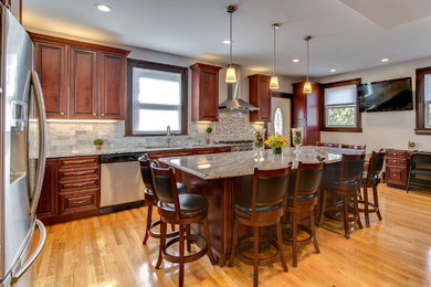 Example of a large trendy u-shaped light wood floor eat-in kitchen design in Boston with an undermount sink, raised-panel cabinets, dark wood cabinets, granite countertops, multicolored backsplash, mosaic tile backsplash, stainless steel appliances and an island