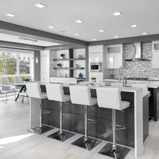 Photo of a large contemporary galley eat-in kitchen in Edmonton with an undermount sink, louvered cabinets, white cabinets, quartz benchtops, multi-coloured splashback, subway tile splashback, stainless steel appliances, porcelain floors, multiple islands, grey floor and white benchtop.