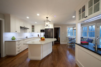 Kitchen - large transitional medium tone wood floor and brown floor kitchen idea in Philadelphia with a farmhouse sink, shaker cabinets, white cabinets, quartz countertops, white backsplash, ceramic backsplash, stainless steel appliances, an island and white countertops