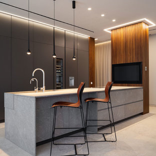 Imagen de cocina de galera, moderna, con fregadero bajoencimera, armarios con paneles lisos, puertas de armario grises, electrodomésticos de acero inoxidable, península, suelo beige y encimeras grises