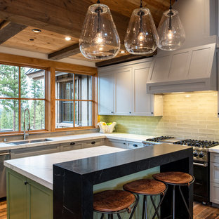 Mid-sized rustic kitchen ideas - Mid-sized mountain style u-shaped medium tone wood floor and brown floor kitchen photo in Other with an undermount sink, shaker cabinets, gray cabinets, solid surface countertops, green backsplash, subway tile backsplash, stainless steel appliances, an island and white countertops