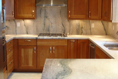 Mid-sized elegant u-shaped travertine floor enclosed kitchen photo in Other with a double-bowl sink, shaker cabinets, medium tone wood cabinets, marble countertops, gray backsplash, stone slab backsplash, stainless steel appliances and a peninsula