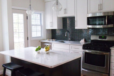 Inredning av ett modernt kök, med stänkskydd i glaskakel, en undermonterad diskho, luckor med infälld panel, bänkskiva i kvarts, svart stänkskydd och rostfria vitvaror