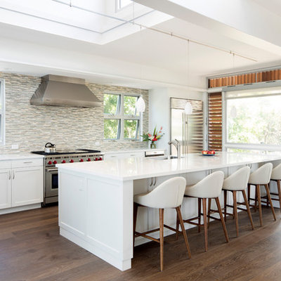 Inspiration for a large tropical l-shaped dark wood floor and brown floor open concept kitchen remodel in Hawaii with an undermount sink, shaker cabinets, white cabinets, multicolored backsplash, matchstick tile backsplash, stainless steel appliances, an island, white countertops and solid surface countertops