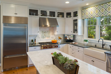 Inspiration for a huge timeless u-shaped light wood floor eat-in kitchen remodel in Providence with an island, shaker cabinets, white cabinets, white backsplash, a farmhouse sink, stainless steel appliances, stone tile backsplash and granite countertops