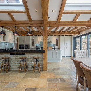 Design ideas for a large country u-shaped open plan kitchen in Other with a drop-in sink, louvered cabinets, granite benchtops, black splashback, black appliances, slate floors, with island, multi-coloured floor and black benchtop.