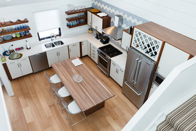 Example of a small transitional light wood floor eat-in kitchen design with a double-bowl sink, blue backsplash, stainless steel appliances and an island