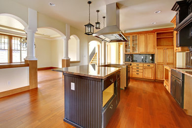 Example of a huge arts and crafts u-shaped medium tone wood floor eat-in kitchen design in Other with an integrated sink, raised-panel cabinets, medium tone wood cabinets, granite countertops, gray backsplash, stone tile backsplash, stainless steel appliances and an island