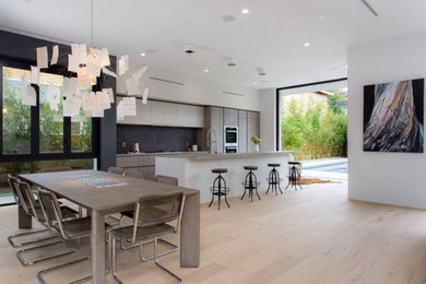 Minimalist light wood floor and beige floor eat-in kitchen photo in Los Angeles with stainless steel appliances and an island