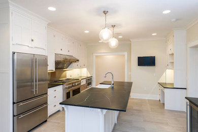 Photo of a large traditional single-wall enclosed kitchen in Philadelphia with a belfast sink, shaker cabinets, white cabinets, soapstone worktops, stainless steel appliances, ceramic flooring and an island.