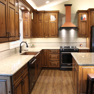 Large rustic open concept kitchen pictures - Large mountain style l-shaped vinyl floor and brown floor open concept kitchen photo in Other with a farmhouse sink, raised-panel cabinets, medium tone wood cabinets, quartz countertops, beige backsplash, glass tile backsplash, black appliances, an island and beige countertops