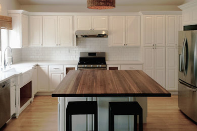 Exempel på ett mellanstort klassiskt kök, med en rustik diskho, vita skåp, bänkskiva i kvarts, vitt stänkskydd, stänkskydd i tunnelbanekakel, rostfria vitvaror, mellanmörkt trägolv, en köksö och luckor med upphöjd panel