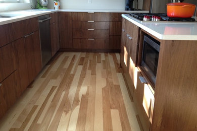 Eat-in kitchen - mid-sized modern l-shaped bamboo floor and beige floor eat-in kitchen idea in Minneapolis with an undermount sink, flat-panel cabinets, dark wood cabinets, solid surface countertops, stainless steel appliances and an island