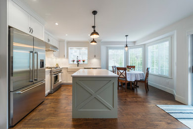 Example of a huge classic l-shaped medium tone wood floor and brown floor eat-in kitchen design in Vancouver with a farmhouse sink, shaker cabinets, white cabinets, quartz countertops, white backsplash, subway tile backsplash, stainless steel appliances, an island and white countertops