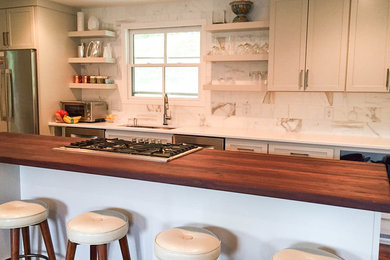 Immagine di una cucina minimal di medie dimensioni con lavello sottopiano, ante bianche, top in legno, paraspruzzi con piastrelle in pietra e elettrodomestici in acciaio inossidabile