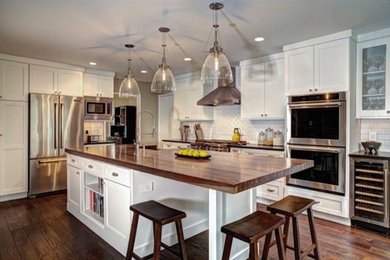 Inspiration for a transitional medium tone wood floor kitchen remodel in Atlanta with recessed-panel cabinets, white cabinets, wood countertops, white backsplash, ceramic backsplash and an island