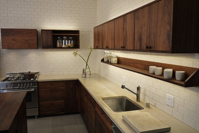 Mid-sized minimalist l-shaped ceramic tile enclosed kitchen photo in San Francisco with an undermount sink, flat-panel cabinets, dark wood cabinets, limestone countertops, white backsplash, subway tile backsplash, stainless steel appliances and an island
