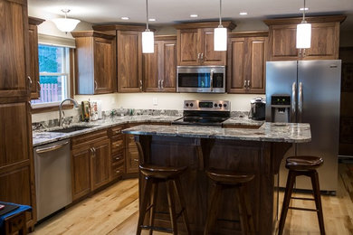 Inspiration for a mid-sized timeless l-shaped light wood floor eat-in kitchen remodel in Cedar Rapids with raised-panel cabinets, medium tone wood cabinets, granite countertops, an island, a single-bowl sink, gray backsplash, stone slab backsplash and stainless steel appliances