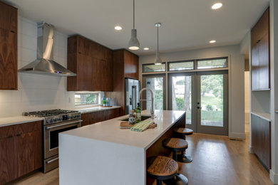 Inspiration for a mid-sized contemporary galley light wood floor kitchen remodel in Nashville with dark wood cabinets, white backsplash, stainless steel appliances and an island