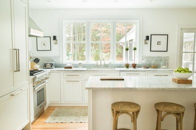 Example of a mid-sized minimalist l-shaped light wood floor eat-in kitchen design in Boston with shaker cabinets, white cabinets, marble countertops and stainless steel appliances