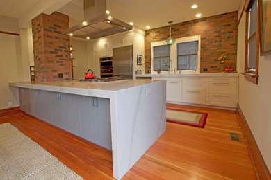 Example of a mid-sized arts and crafts u-shaped medium tone wood floor eat-in kitchen design in Seattle with an undermount sink, shaker cabinets, quartz countertops, stainless steel appliances and an island