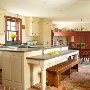 Photo of a medium sized country single-wall kitchen/diner in Philadelphia with raised-panel cabinets, beige cabinets, brick flooring, an island, a belfast sink, integrated appliances, red floors, concrete worktops and grey worktops.
