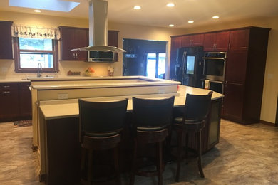 Eat-in kitchen - eat-in kitchen idea in Milwaukee with an undermount sink, shaker cabinets, dark wood cabinets, quartz countertops, stainless steel appliances, an island and beige countertops