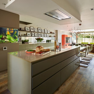 Offene Moderne Küche mit flächenbündigen Schrankfronten, Mineralwerkstoff-Arbeitsplatte, Rückwand aus Spiegelfliesen, braunem Holzboden und Kücheninsel in London