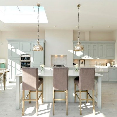 Eat-in kitchen - transitional galley eat-in kitchen idea in London with a farmhouse sink, shaker cabinets, blue cabinets, stainless steel appliances and an island