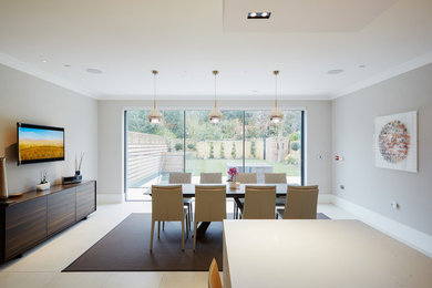 Photo of a large contemporary kitchen/diner in London with white cabinets, ceramic flooring, a breakfast bar and grey floors.