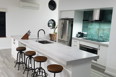 Immagine di una cucina minimalista di medie dimensioni con lavello a doppia vasca, ante bianche, top in cemento, paraspruzzi verde, paraspruzzi con piastrelle in ceramica, elettrodomestici in acciaio inossidabile e pavimento grigio