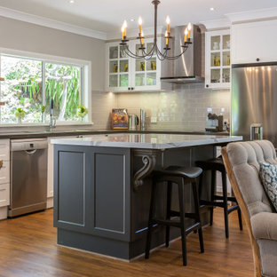 Design ideas for a large transitional l-shaped open plan kitchen in Melbourne with a double-bowl sink, shaker cabinets, white cabinets, quartz benchtops, grey splashback, subway tile splashback, stainless steel appliances, vinyl floors, with island, brown floor and grey benchtop.