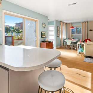 This is an example of a midcentury kitchen in San Francisco with an undermount sink, flat-panel cabinets, quartz benchtops, blue splashback, subway tile splashback, stainless steel appliances, vinyl floors and white benchtop.
