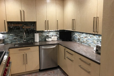 Small trendy u-shaped cork floor enclosed kitchen photo in DC Metro with an undermount sink, flat-panel cabinets, yellow cabinets, recycled glass countertops, glass tile backsplash, stainless steel appliances and no island