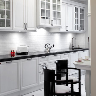 Inspiration for a traditional galley eat-in kitchen in Other with an undermount sink, glass-front cabinets, white cabinets, granite benchtops, white splashback, porcelain splashback, stainless steel appliances and white floor.