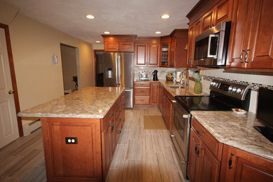 Eat-in kitchen - large traditional l-shaped light wood floor eat-in kitchen idea in Providence with raised-panel cabinets, dark wood cabinets, granite countertops, white backsplash, ceramic backsplash, stainless steel appliances and an island