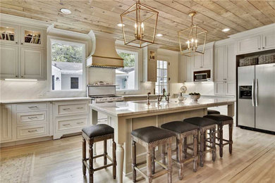Large elegant u-shaped light wood floor, brown floor and wood ceiling eat-in kitchen photo in Austin with recessed-panel cabinets, white cabinets, an island and a drop-in sink