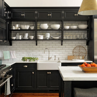 Eat-in kitchen - large transitional l-shaped medium tone wood floor and brown floor eat-in kitchen idea in DC Metro with a farmhouse sink, beaded inset cabinets, black cabinets, white backsplash, subway tile backsplash, stainless steel appliances, an island and quartzite countertops
