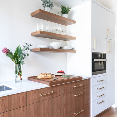 Kitchen pantry - mid-sized 1960s galley medium tone wood floor and brown floor kitchen pantry idea in DC Metro with an undermount sink, flat-panel cabinets, medium tone wood cabinets, quartzite countertops, white backsplash, porcelain backsplash, stainless steel appliances, no island and white countertops