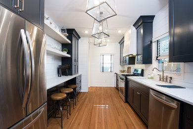 Example of a mid-sized transitional galley light wood floor kitchen design in Indianapolis with a drop-in sink, black cabinets, quartz countertops, stainless steel appliances and no island