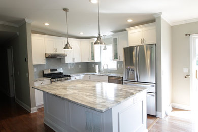 Example of a mid-sized transitional l-shaped light wood floor eat-in kitchen design in New York with a single-bowl sink, shaker cabinets, white cabinets, marble countertops, gray backsplash, glass tile backsplash, stainless steel appliances and an island