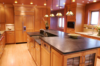 Mid-sized arts and crafts u-shaped light wood floor eat-in kitchen photo in Denver with a farmhouse sink, raised-panel cabinets, light wood cabinets, solid surface countertops, white backsplash, subway tile backsplash, stainless steel appliances and an island