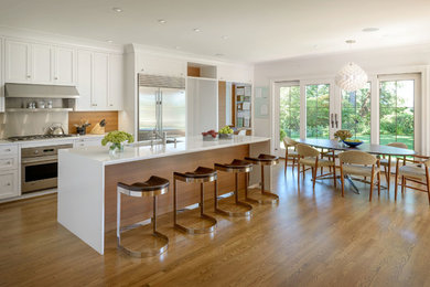 Example of a large transitional l-shaped medium tone wood floor and brown floor eat-in kitchen design in Seattle with flat-panel cabinets, medium tone wood cabinets, quartz countertops, an island, brown backsplash, an undermount sink, wood backsplash and stainless steel appliances