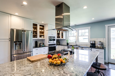 Design ideas for an expansive classic u-shaped kitchen/diner in Baltimore with a belfast sink, shaker cabinets, engineered stone countertops, white splashback, ceramic splashback, stainless steel appliances, dark hardwood flooring and an island.